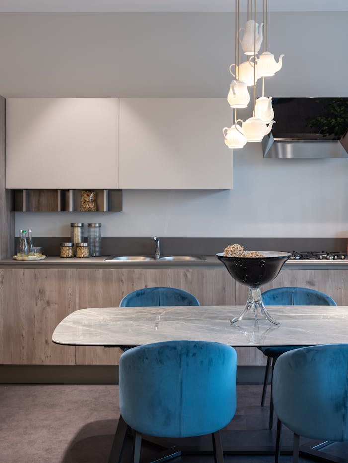 Interior of modern kitchen with chairs near table with bowl and cabinet and kitchenware near sink